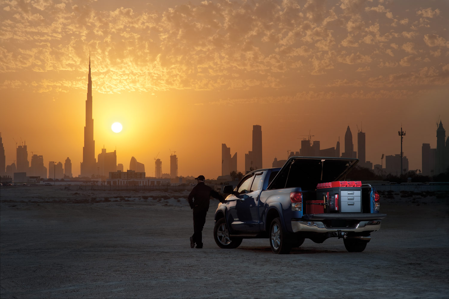 Camioneta azul con sistema de estanterías Modul System en un desierto frente a una puesta de sol.